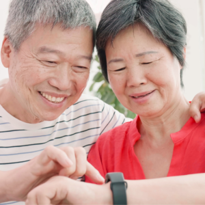 Elderly couple using smartwatch for wearable fitness preventive care, tracking heart rate and daily activity.