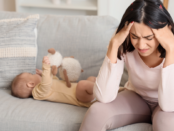 Stressed new mother sitting down with her head in her hands, reflecting postpartum anxiety